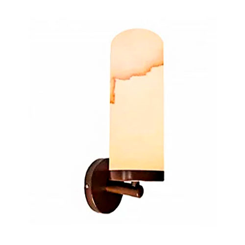 Esta arandela possui uma base circular escura que sustenta um corpo vertical cilíndrico com o topo arredondado. O difusor tem textura de mármore translúcido em tons de bege e marrom, emitindo uma luz suave e quente. O design une a robustez da pedra à leveza da iluminação decorativa