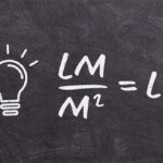 A imagem, que se assemelha a um quadro-negro, mostra uma lâmpada desenhada à esquerda e uma fórmula matemática à direita. A fórmula é M 2 LM =LX. Explicação concisa para um cego (máximo 300 caracteres): É um desenho de lousa preta. Há uma lâmpada acesa desenhada à esquerda. À direita, a fórmula do cálculo de iluminância (lux): lúmens (LM) dividido por metros quadrados (M 2 ) é igual a lux (LX). Isso representa como se calcula a quantidade de luz numa área.