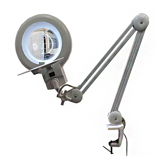 Este é um lupa de mesa com luminária LED, na cor cinza. Possui uma lente de aumento circular iluminada por uma luz fria e branca. O corpo está preso a um braço articulado que pode ser ajustado em várias posições e é fixado a uma base tipo grampo de mesa. É usada para trabalhos detalhados, como eletrônica ou estética.